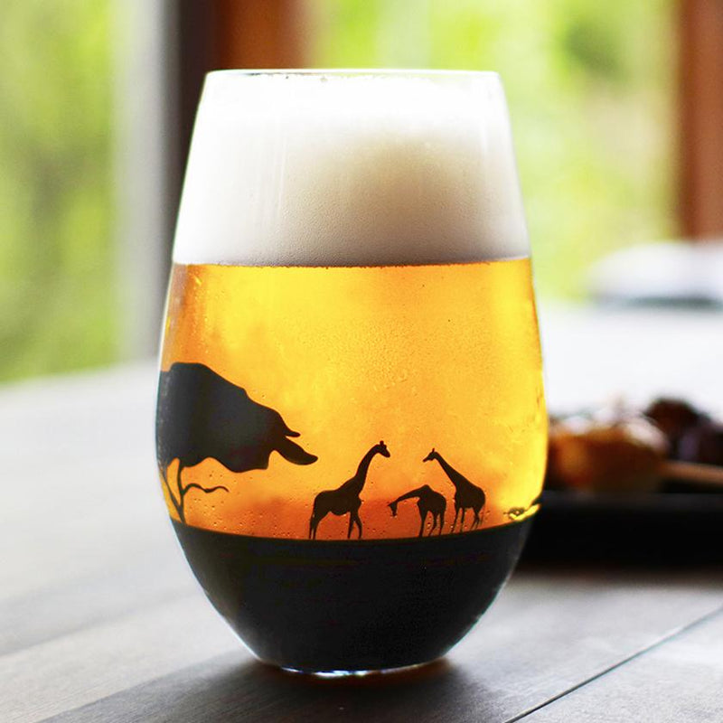 ビールを注いだ夕日を眺めるキリンのグラス——液面越しにキリンと象のシルエットが浮かぶガラスタンブラー｜丸モ高木陶器